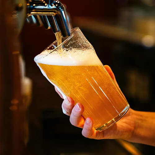 Main du barman remplissant une pinte de bière fraîche au bar au restaurant La Table de Trois à Bordeaux