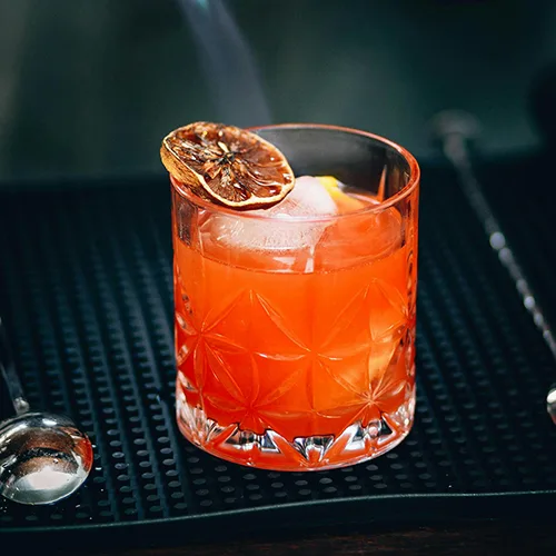 Cocktail Mai Tai sur fond noir avec de la glace et du citron au restaurant La Table de Trois à Bordeaux
