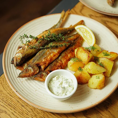 Éperlans frits croustillants servis avec pommes de terre dorées au restaurant La Table de Trois à Bordeaux
